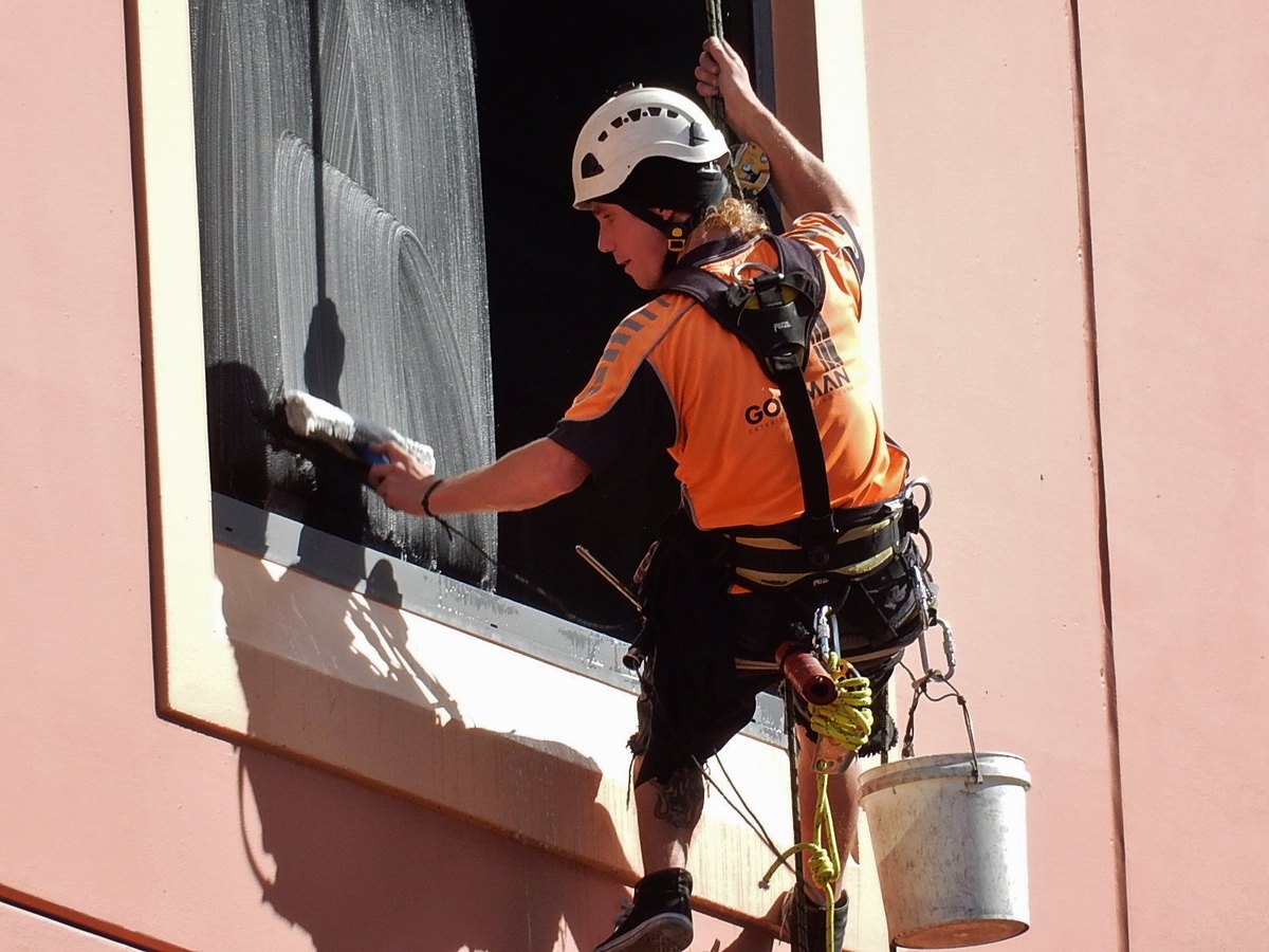 A window cleaner scrubbing a soapy window