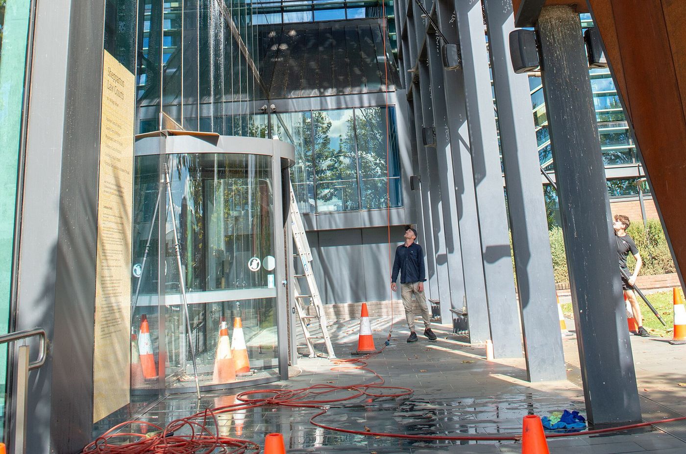 Window cleaners on the ground using tall water-fed poles