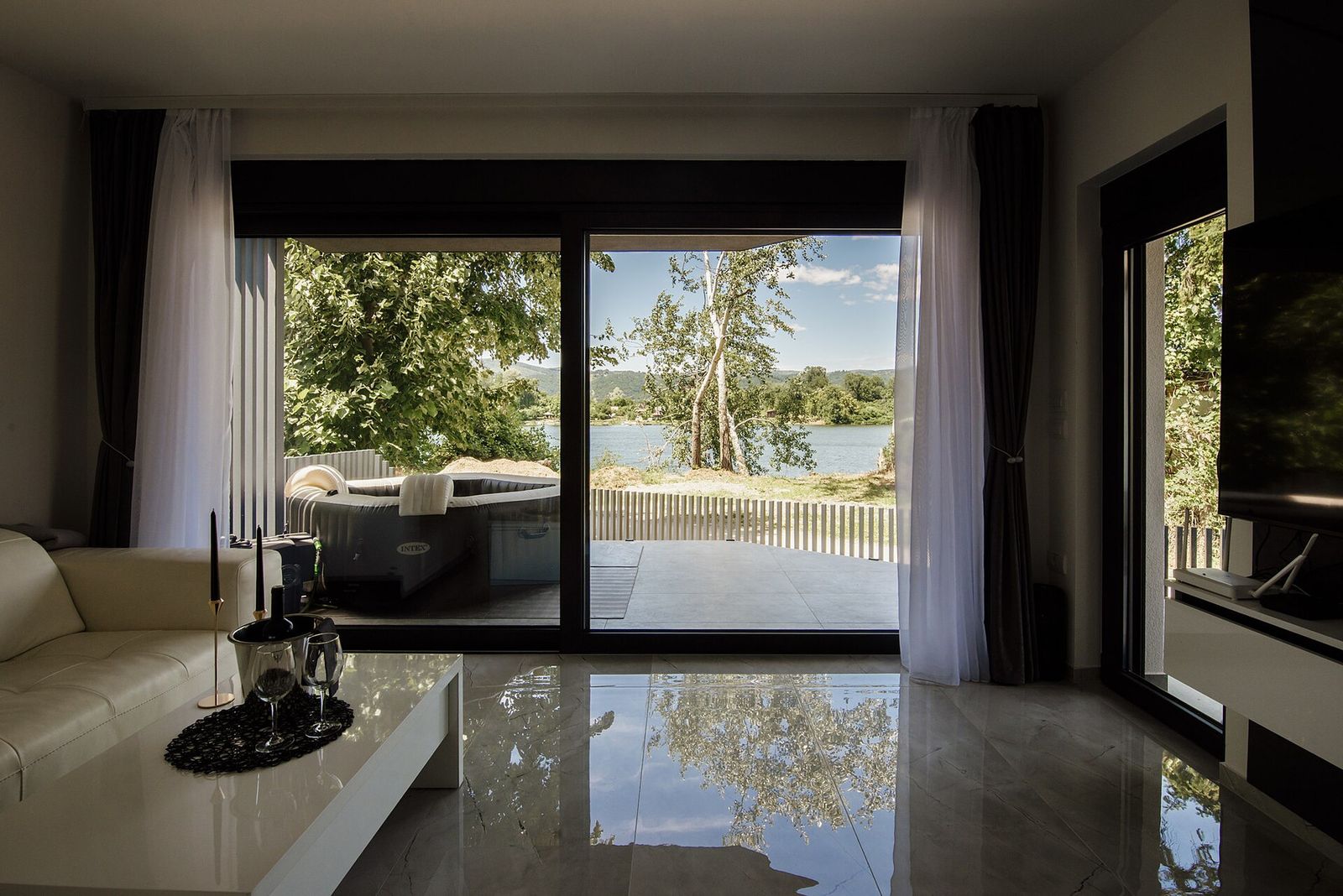 A bright living room looking out through spotless floor-to-ceiling glass